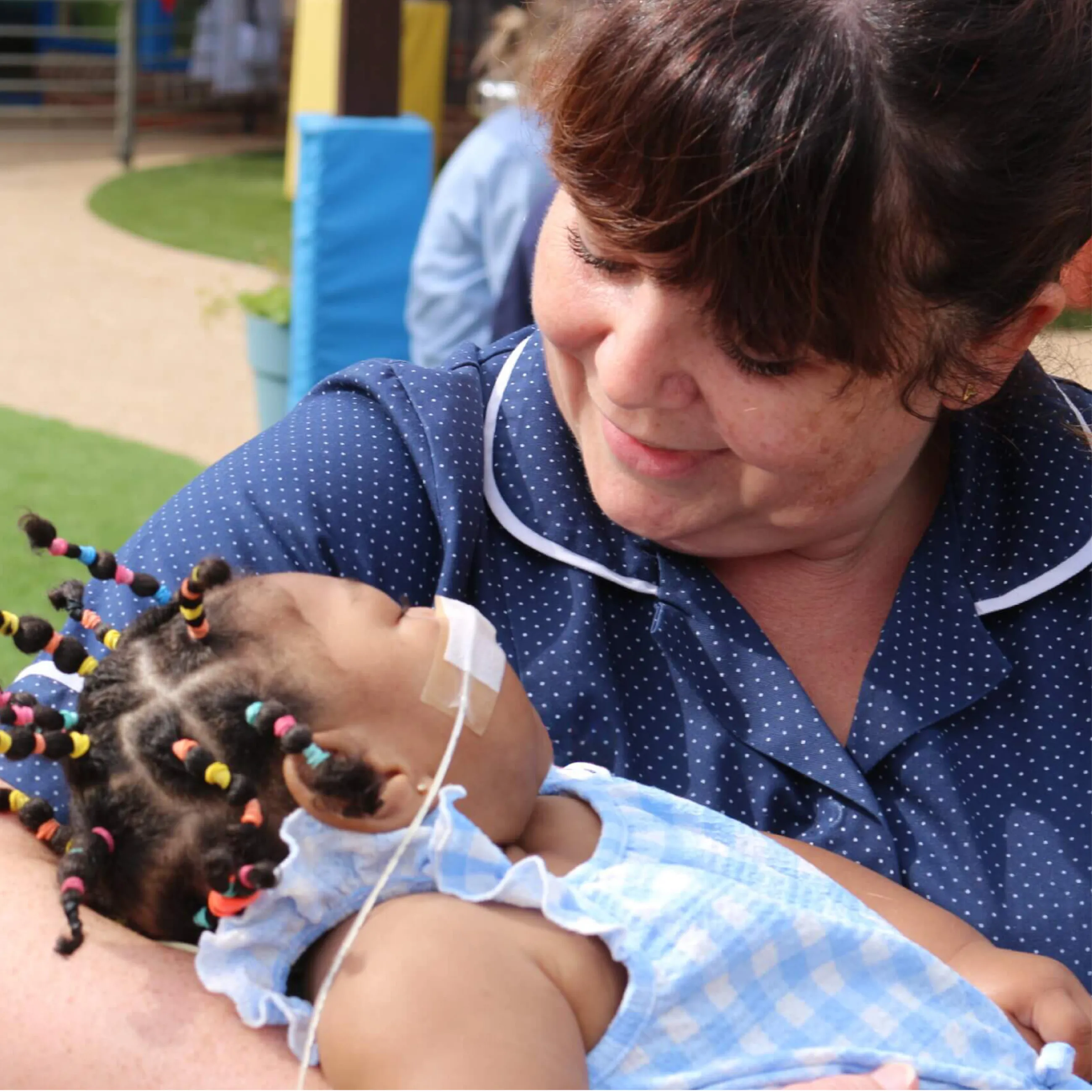 Keech Hospice nurse holding a young girl in her arms while smiling at her