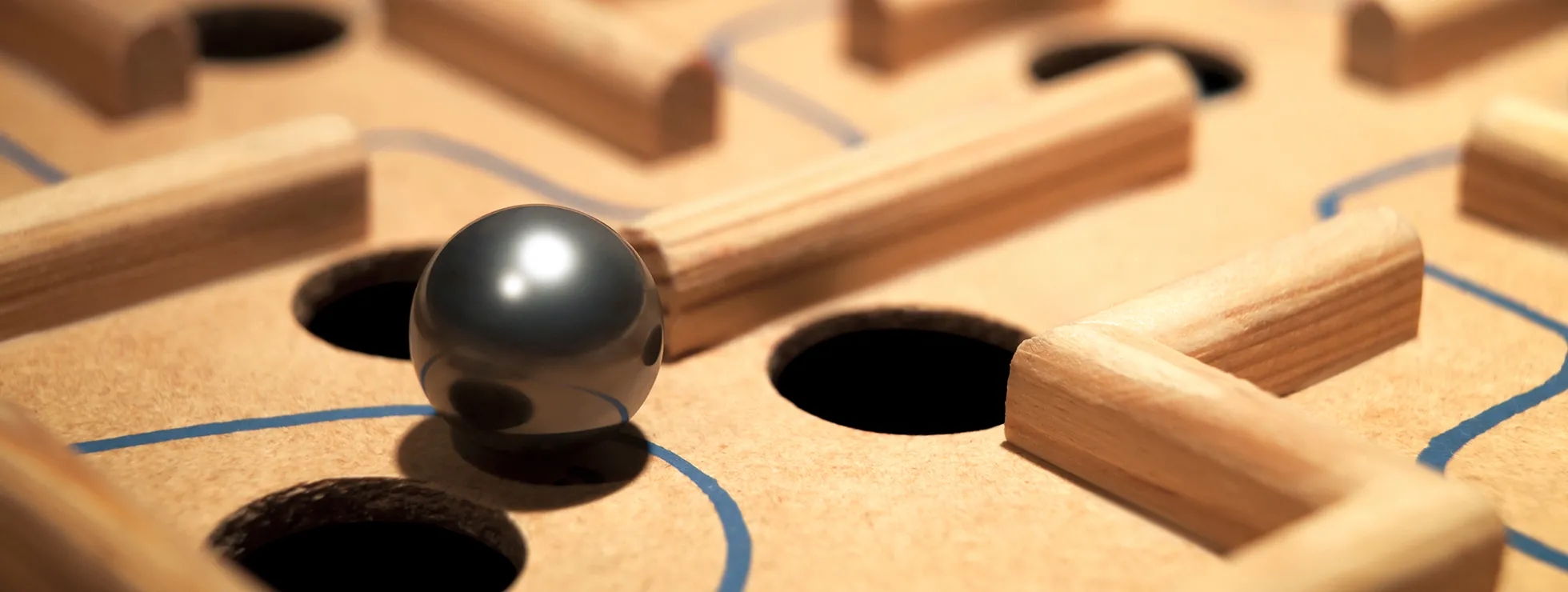 Selective focus macro of a ball navigating it's way through a labyrinth board maze while trying to avoid falling through the surrounding traps